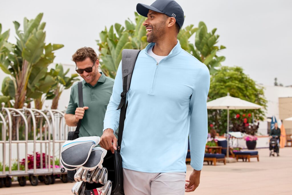 Two men walking, one in light blue quarter-zip